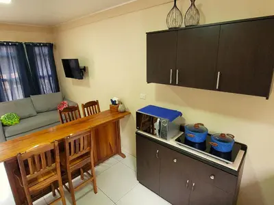 a kitchen with a counter with a microwave and a living room at Arenal Honey House in Fortuna