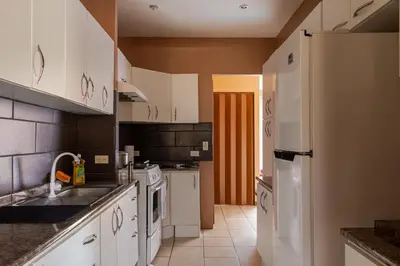 a kitchen with white cabinets and a white refrigerator at Cozy 3 Bedroom House 5mins from the Airport in Alajuela City