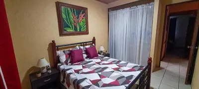 a bedroom with a bed with purple pillows at Cozy 3 Bedroom House 5mins from the Airport in Alajuela City