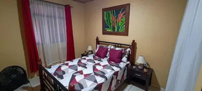 a bedroom with a bed with purple pillows at Cozy 3 Bedroom House 5mins from the Airport in Alajuela City