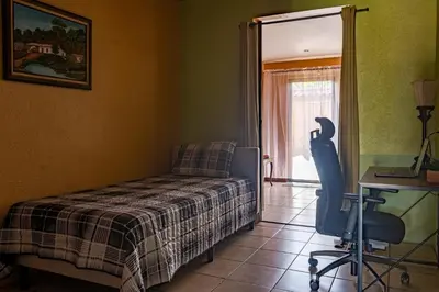 a bedroom with a bed and a desk and a chair at Cozy 3 Bedroom House 5mins from the Airport in Alajuela City