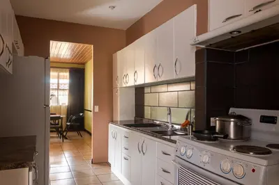 a kitchen with white cabinets and a stove top oven at Cozy 3 Bedroom House 5mins from the Airport in Alajuela City