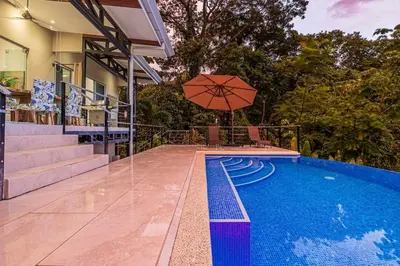 a swimming pool with an umbrella next to a house at Ocean View Villa With Pool and Spectacular Sunsets in Ballena