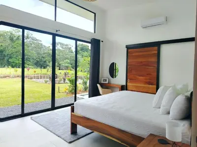 a bedroom with a large bed and sliding glass doors at Villa Luxury Volcano Paradise Retreat in Fortuna