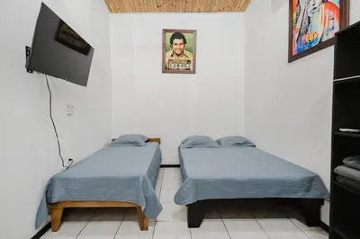 two beds in a room with a picture on the wall at Apartamento Frigia 2 in Quepos