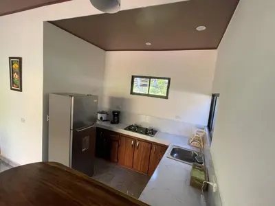 a kitchen with a stainless steel refrigerator and wooden cabinets at Villas Casa Paz in Cóbano
