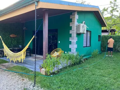 a man standing in front of a green house with a hammock at Villas Casa Paz in Cóbano