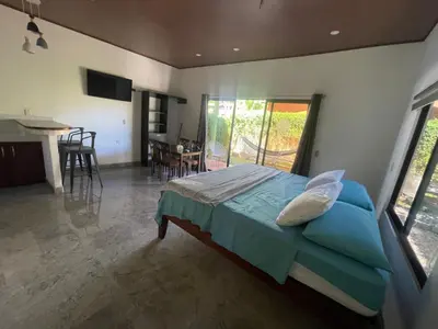 a bedroom with a bed and a kitchen and a table at Villas Casa Paz in Cóbano