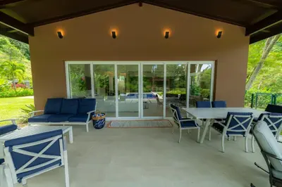 a patio with blue chairs and a white table at Casa Forest 4 bdrs private pool in Los Suenos in Herradura