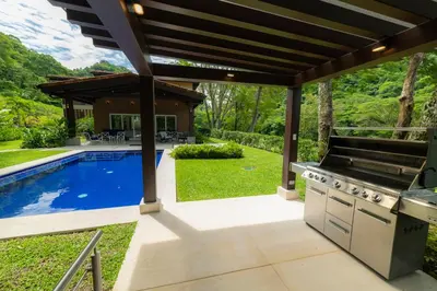 an outdoor kitchen with a grill and a swimming pool at Casa Forest 4 bdrs private pool in Los Suenos in Herradura