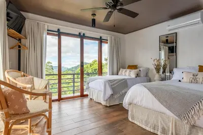 a bedroom with two beds and a window with a view at Yaloco House Monteverde in Monteverde Costa Rica