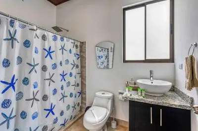 a bathroom with a sink and a toilet and a shower curtain at Casa Maiki Your Private Retreat in Uvita Center in Uvita