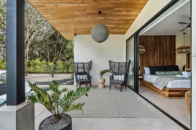 a bedroom with a bed and two chairs at Casa Ola Aloha in Playa Avellana