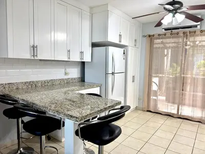 a kitchen with white cabinets and a counter with bar stools at Coco Maya 2b2b Villa in Coco