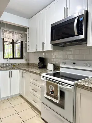 a kitchen with white cabinets and a stove and a microwave at Coco Maya 2b2b Villa in Coco