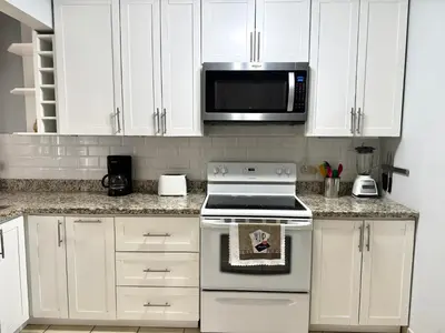a kitchen with white cabinets and a stove and a microwave at Coco Maya 2b2b Villa in Coco