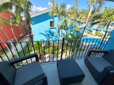 a balcony with two chairs and a blue building at Coco Maya 2b2b Villa in Coco