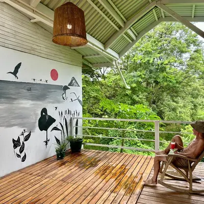 a man sitting in a chair on a deck at Hotel Tama Lodge in Tamarindo