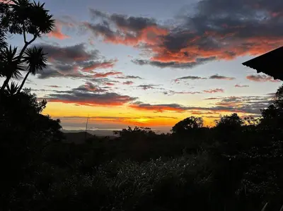 a sunset in the sky with trees and clouds at Casita Acantilado - Timber Frame Tiny House in Monteverde Costa Rica