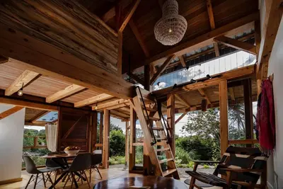 a house with a ladder in the middle of a room at Casita Acantilado - Timber Frame Tiny House in Monteverde Costa Rica