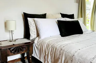 a bed with black and white pillows and a table at Casa Kiv Turrialba Centro in Turrialba