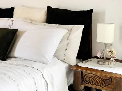 a bed with black and white pillows and a table with a lamp at Casa Kiv Turrialba Centro in Turrialba