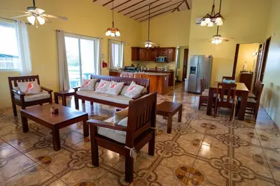 a living room with a couch and tables and a kitchen at Guayabo Animal Rescue & Sanctuary in Hacienda Miravalles