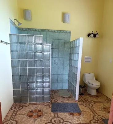 a bathroom with a toilet and a shower with glass doors at Guayabo Animal Rescue & Sanctuary in Hacienda Miravalles