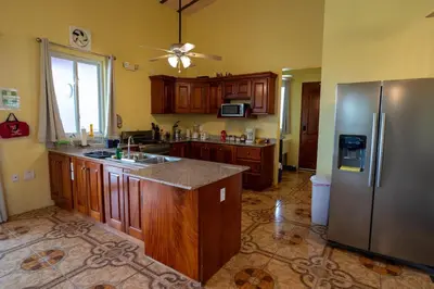 a kitchen with wooden cabinets and a stainless steel refrigerator at Guayabo Animal Rescue & Sanctuary in Hacienda Miravalles