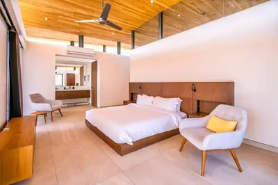 a bedroom with a bed and a chair at Nimbu West in Tamarindo
