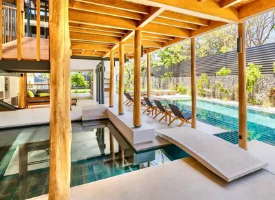 a house with a swimming pool with a wooden roof at Nimbu West in Tamarindo