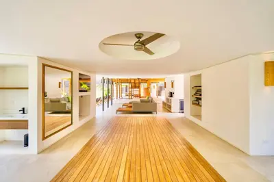 a living room with a ceiling fan and a wooden floor at Nimbu West in Tamarindo