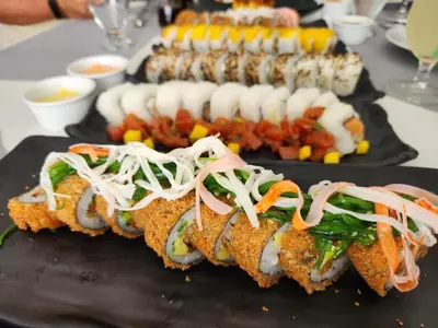 two plates of food on a table with sushi at Hotel Puerto Limón CR in Puerto Limón