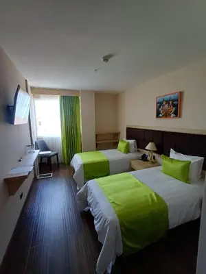 a hotel room with two beds with green sheets at Hotel Puerto Limón CR in Puerto Limón