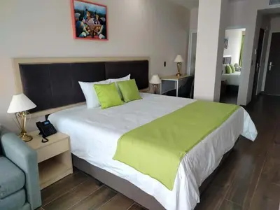 a bedroom with a large bed with a green blanket at Hotel Puerto Limón CR in Puerto Limón