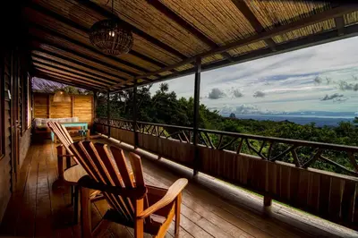 a porch with two chairs and a table on a balcony at Casa Cabuya - Retro Style with Gulf View in Monteverde in Monteverde Costa Rica