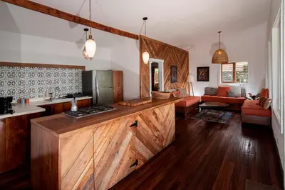 a kitchen with wooden counter tops and a living room at Casa Cabuya - Retro Style with Gulf View in Monteverde in Monteverde Costa Rica