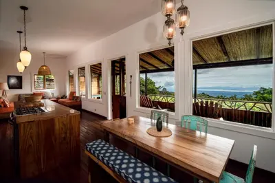 a living room with a table and some windows at Casa Cabuya - Retro Style with Gulf View in Monteverde in Monteverde Costa Rica