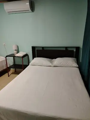 a large white bed in a room with a side table at Cabinas El Jardin in Paquera