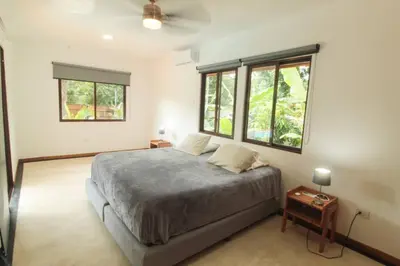 a bedroom with a bed and two windows at Casa Manzanillo Surf in Manzanillo