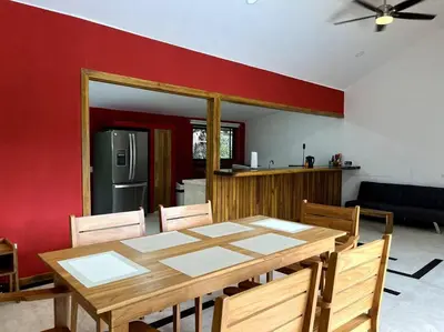 a dining room with a wooden table and a kitchen at Casa Manzanillo Surf in Manzanillo