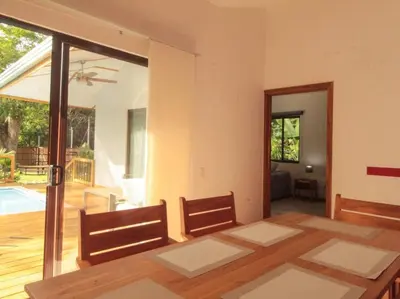 a dining room with a table and chairs and a patio at Casa Manzanillo Surf in Manzanillo