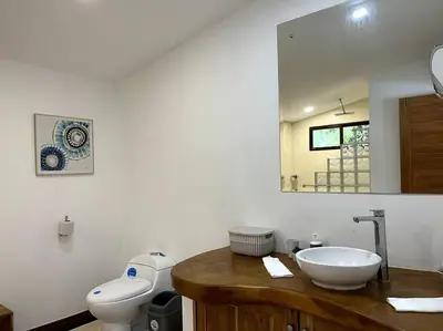 a bathroom with a sink and a toilet and a mirror at Casa Manzanillo Surf in Manzanillo