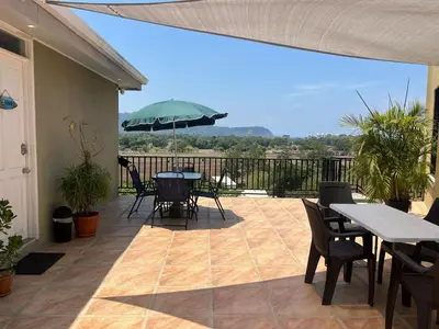 a patio with tables and chairs and an umbrella at Casa Bella Vista Jaco #1 in Jacó