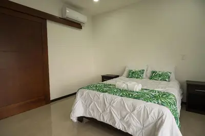a bedroom with a bed with green and white sheets at Volcan Hule Lodging in Río Cuarto