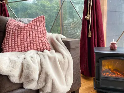a couch with a blanket next to a fireplace at FéLIZA Rainforest Domes in Monteverde Costa Rica