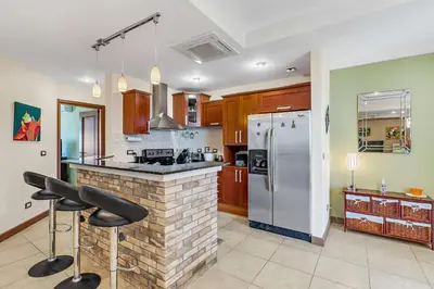 a kitchen with a white refrigerator and a counter with stools at Casa feng shui in Tamarindo