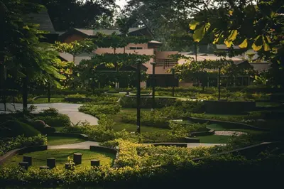 a garden with trees and a building in the background at Ciudad del Mar 31 in Jacó