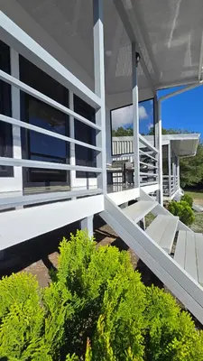 a white house with a porch and some bushes at Cattleya Living Studio in Monteverde Costa Rica