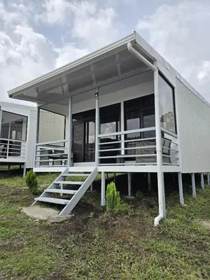 a white house with large windows on a field at Cattleya Living Studio in Monteverde Costa Rica